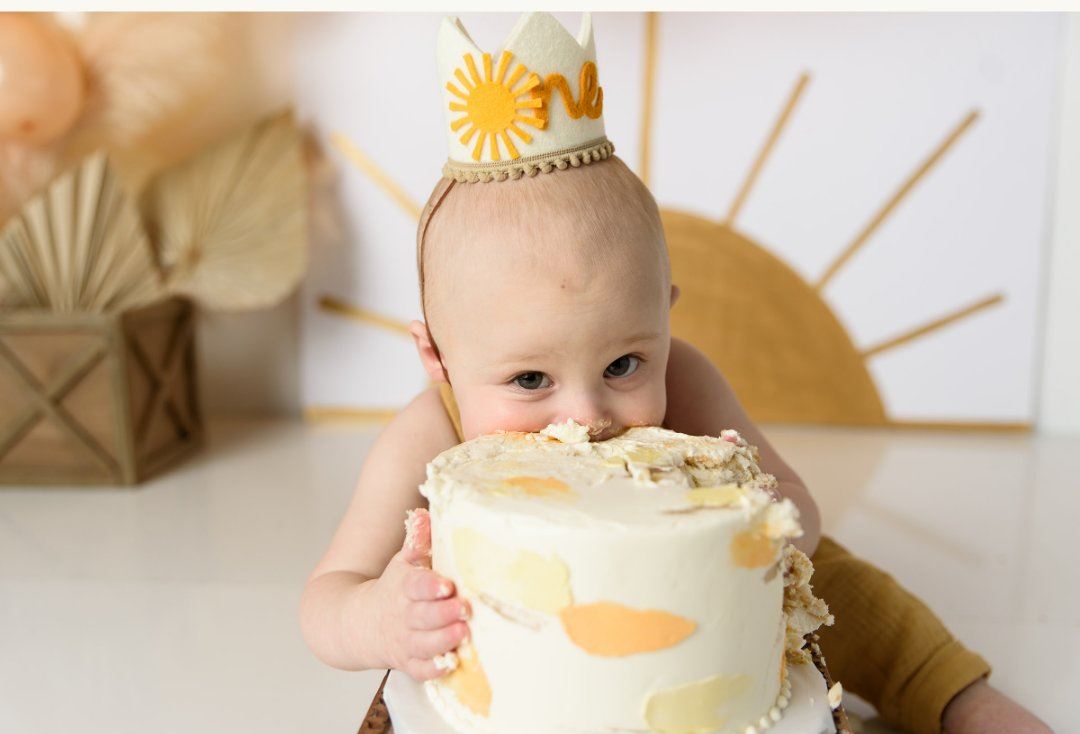 First birthday cake smash session in a boho style theme with little boy eating a cake